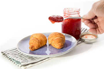 two cheese croissants on a plate with a jar of home made strawberry jam isolated on white