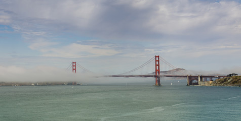 The Golden Gate Bridge with foggy cloudy skies as seen from Land's End trail in Richmond District. San Francisco, California, USA.