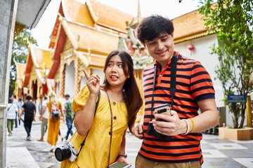 Obraz premium young thai couple looking at smartphone in front of Wat Phrathat Doi Suthep temple in chiang mai thailand