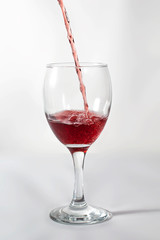 Pouring red wine on a wine glass. frozen movement while splashing with the cup shadow on the right side.
