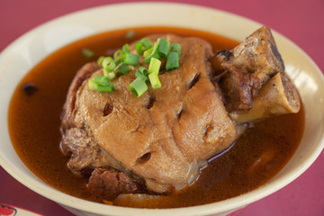 Slow cooked pork leg with soup in blow on the table