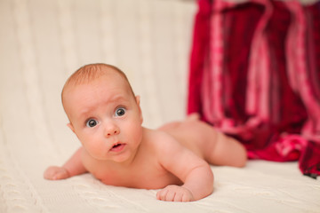 Portrait of four month caucasian baby on knitted plaid in selective focus.