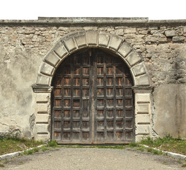 Fototapeta na wymiar Medieval gate of an old castle surrounded by a stone wall. Architectural object, vintage door.