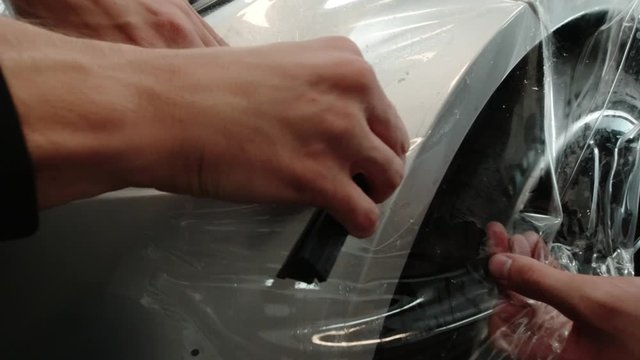 Close up to PPF installation process on silver sports car. PPF is a Paint Protection Film which protect paint from scratches and stone chips.