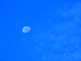 早朝の青空に輝く白い月、薄雲が煙のように立ち昇る、月イメージ素材