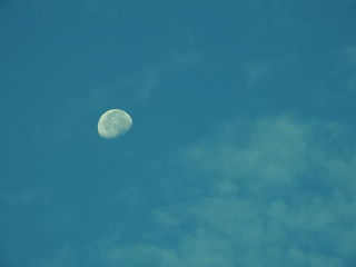 早朝の青空に輝く白い月、薄雲が煙のように立ち昇る、月イメージ素材