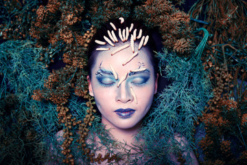 Fototapeta na wymiar Art portrait of woman inside green nature leafs with scary worms on face