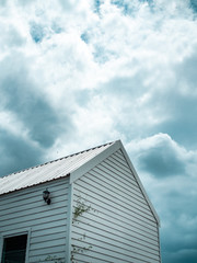 White wooden cabin against the cloud and blue sky background.