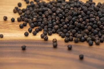 Dry heap black pepper isolated on wooden chopper board