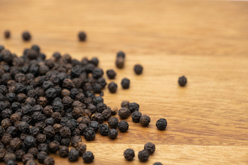 Dry heap black pepper isolated on wooden chopper board