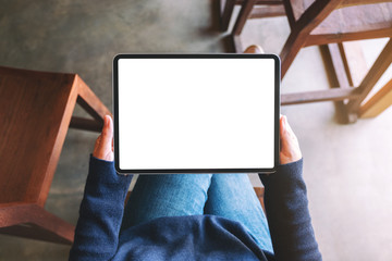 Top view mockup image of a woman holding black tablet pc with blank white screen while sitting in cafe