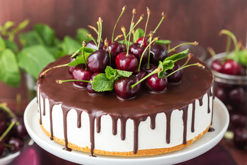 White jelly cake with vanilla base and chocolate topping decorated fresh cherries on a wooden background