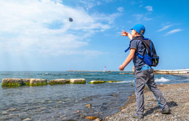 A boy throws stones at sea.