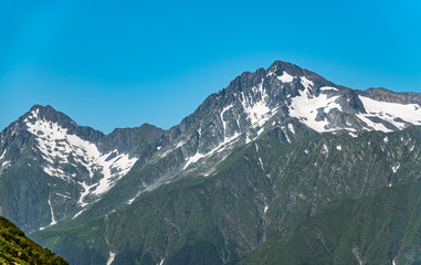 High mountains with green slopes and snowy peaks.