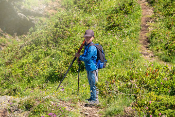 A boy traveler is standing on the path to the top of the mountain range