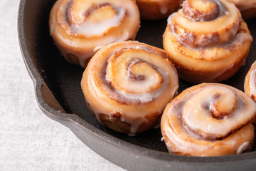 Homemade baked cinnamon rolls baked in an iron skillet with icing