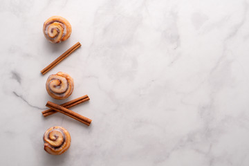 Homemade baked cinnamon rolls with marble slab background and space for text.