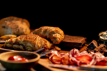 Selective focus on Croissant in wooden dish on table in the dark, grunge style.