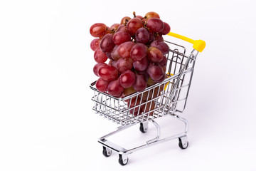 Fresh red grapes in a yellow cart. isolated on white background.