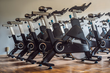 Aerobics spinning exercise bikes gym room with many in a row