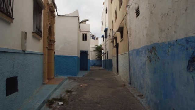 A steadicam shot of a tight street with blue and white walls in Chefchaouen city, Morocco