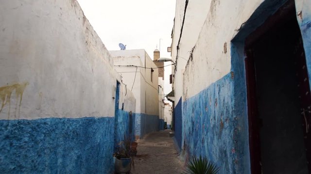 Steadicam shot of a tight street with blue and white walls in Chefchaouen city, Morocco