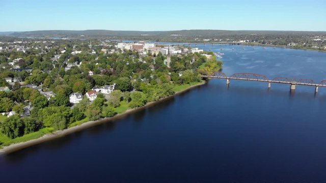 AERIAL: Flying Over The Saint John River Toward Downtown Fredericton. Walking Bridge In The Foreground.