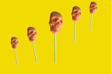 caramel on a stick in the shape of a skull on a yellow background