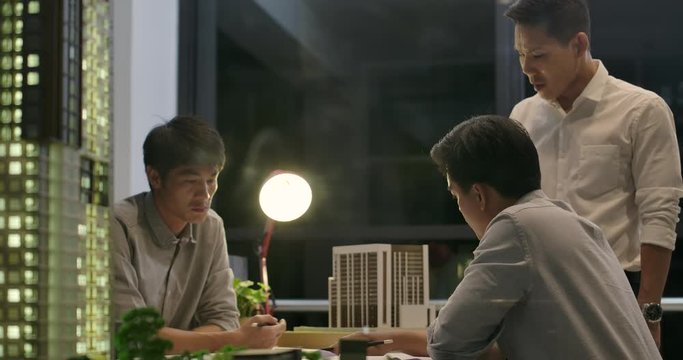 Team of creative architects getting rebuke from his boss in the office at night.