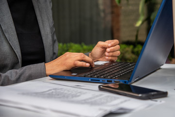 manos de mujer morena trabajadora con telefono celular y laptop azul en oficina