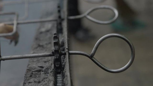 A slow-motion, extreme closeup shot of a split duck carcass in an iron skewer placed over a burning charcoal fire in a rotisserie.