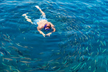 A man swims in the blue water of the sea