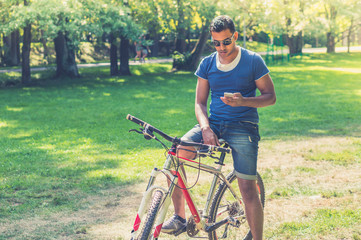 Young Indian man on bicycle watching smartphone