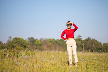 Hipster Asian woman in red and sunglasses on white flower and grass field