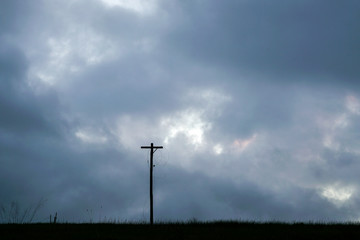 Cross silhouette in a field on a dark cloudy day