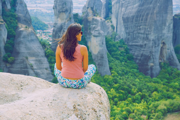 City Meteora, Greek Republic. Big mountains and girl sit on rock. 12. Sep. 2019. Travel photo.