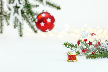 green christmas tree branches with glass balls and glowing light garlands against white background