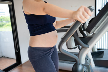 Fototapeta na wymiar Cropped image of pregnant woman in fitness clothes exercising