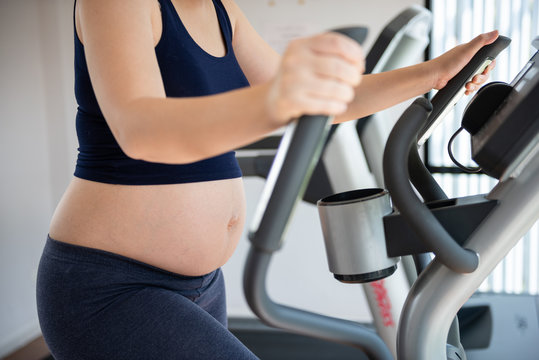 Cropped image of pregnant woman in fitness clothes exercising
