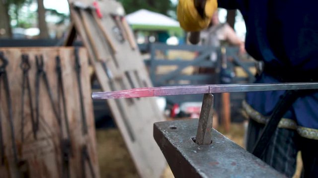 Blacksmith hammering and forging a molten piece of metal