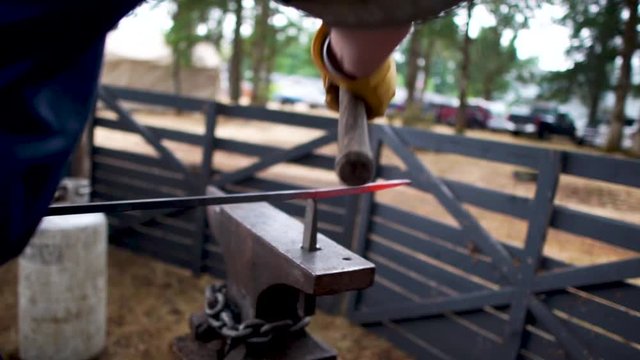 Blacksmith hammering and forging a molten piece of metal
