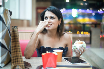 Woman having food and drink after shopping at mall