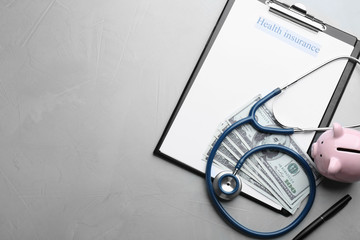 Medical insurance form with money, stethoscope and piggybank on grey background, flat lay. Space for text