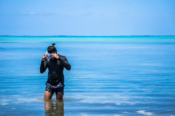 Indian man with snorkeling equipment going out of water