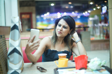 Stylish woman taking selfie using mobile phone at cafe