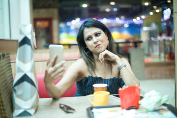 Stylish woman taking selfie using mobile phone at cafe