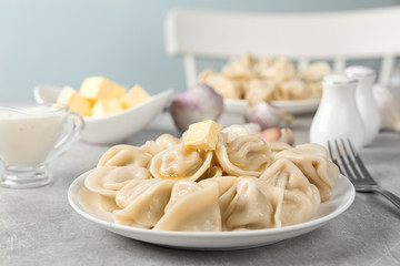 Tasty dumplings with butter on light grey table against blurred background
