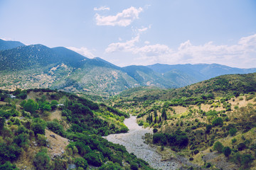 Naklejka premium Greek Republic. Fields and mountains, grass and trees. In the distance mountains and sky. 13. Sep. 2019. Travel photo.