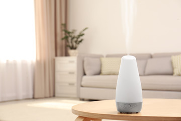 Modern essential oil diffuser on table in room. Space for text