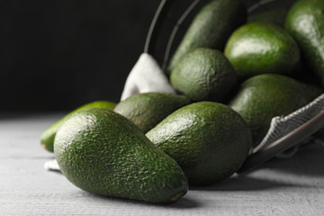 Delicious ripe avocados on grey wooden table against dark background